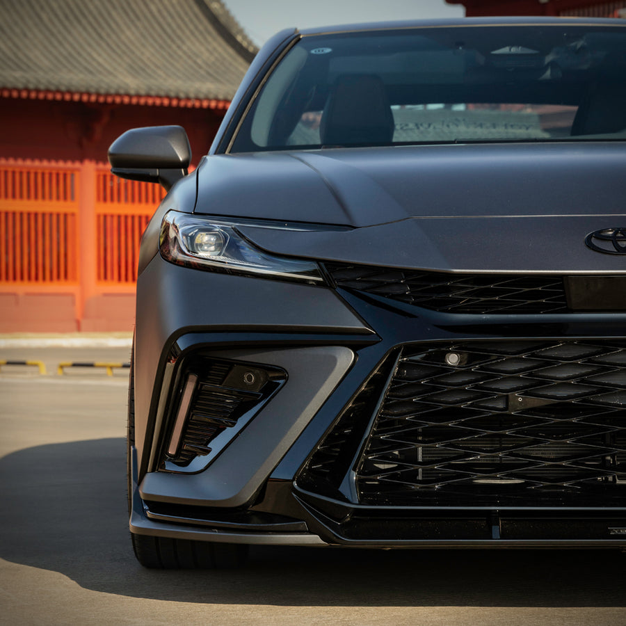 Close-up of the YOFER front bumper on a grey 2025-2026 Toyota Camry,
showing the diamond mesh grille, corner intake and LED daytime running light