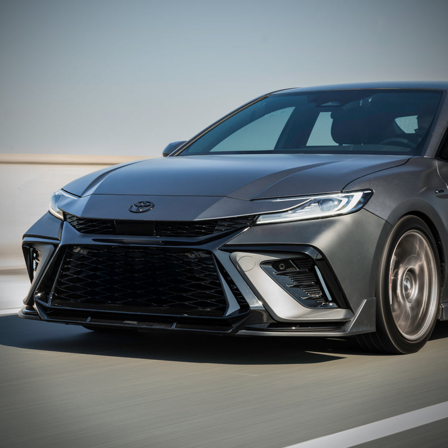 Close-up of the YOFER front bumper on a silver 2025-2026 Toyota Camry
in motion, showing the corner intake, splitter and wheel